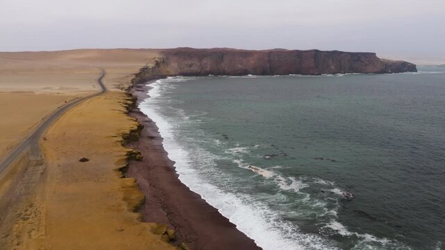 Sweeping beach arc fades into haze as surf traces the boundary between sand and sea at Paracas, aerial dolly