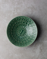 Top view of green ceramic plates on a cement countertop, handmade green ceramic plate on a grey background