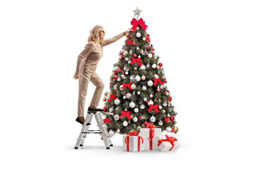 Woman on a ladder hanging a red bow on a christmas tree © Ljupco Smokovski