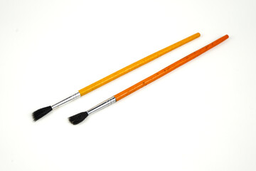 Two new small black watercolor paintbrushes with yellow and orange handles on white