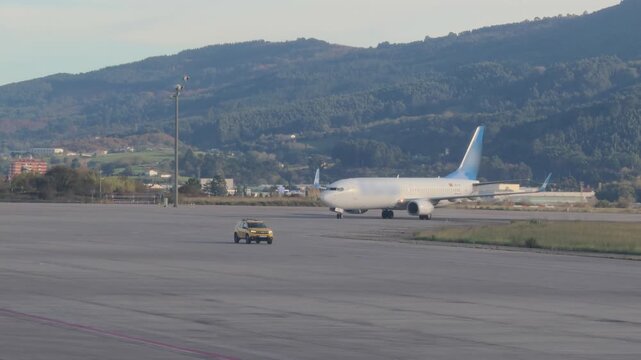 Yellow Airport Service Car Passing Widebody Jet on Runway
