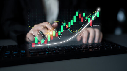 A business professional examines stock market trends using a digital graph interface on a keyboard, highlighting growth in a contemporary office environment. Impute