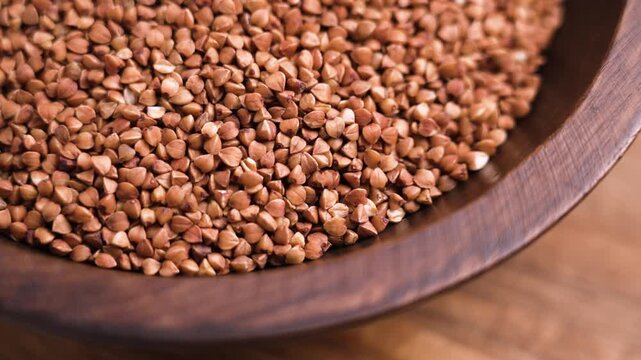 Brown uncooked buckwheat grains falling in slow motion. Dietary organic ingredient