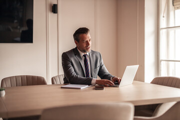 Fototapeta premium Professional Man in Suit Working on Laptop in Modern Office