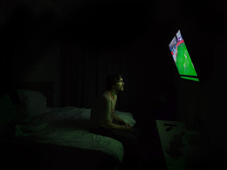 Lonely man watching TV in dark room, depressive atmosphere, green screen glow.