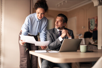 Fototapeta premium Business Professionals Collaborating and Discussing Reports in Modern Office Setting