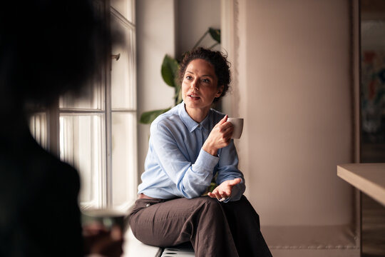 Woman Conversing Over Coffee in Relaxed Indoor Setting