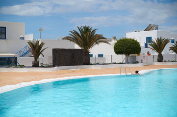 Fototapeta premium Vacationers enjoying luxurious poolside experience at a high-end resort in Lanzarote, Canary Islands, under sunny blue skies