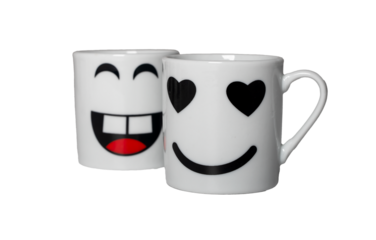 Two white mugs display expressive cartoon faces, one laughing and one smiling with heart-shaped eyes