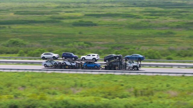 Car carrier semi truck transporting multiple vehicles across the United States on a major highway.