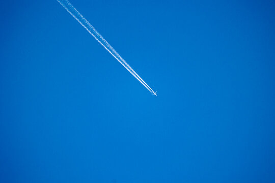 A beautiful white plane crossing clear blue skies over Latvia, Europe. Sunny day with plane trails.