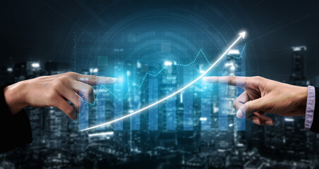This image depicts two hands pointing towards a digital graph showing growth, symbolizing collaboration and success in business. The urban night setting adds a modern touch. Impute