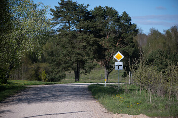 Rural Latvian gravel road with turn warning signs