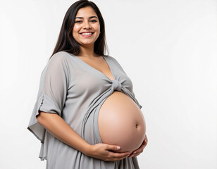 Happy pregnant Indian woman smiling while holding her belly in bright minimal studio portrait