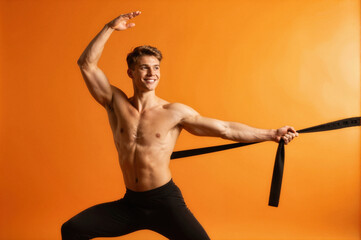 shirtless male dancer holding black ribbon in dynamic pose against orange background