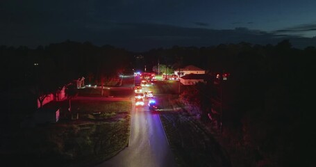 Firefighters investigating fire hazard on residential street in North Port in Florida. Bright flashing lights at night.
