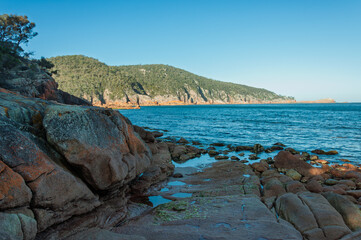Tasmania shore scene with rounded coastal rocks and calm inlet water, perfect for ecotourism promotion, national park campaigns, hiking materials and nature-focused editorials.