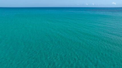 Obraz premium Aerial view of the crystal clear, turquoise sea. The sea stretches to the horizon with colours ranging from azure to dark blue. Ideal for concept of tropical seas. Sunny summer morning. 