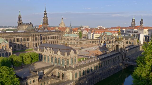Majestic aerial view of the Dresden Zwinger: A baroque masterpiece featuring the Wall Pavilion, galleries, and the historical city skyline in the background. The scene is sunny and richly detailed.