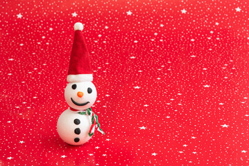 Happy little handmade snowman with Santa hat on red background with white stars and copy space