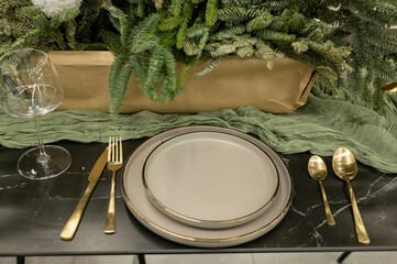 Elegant holiday table setting with gold cutlery and greenery