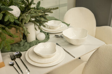 Elegant holiday table setting with white dishware and greenery