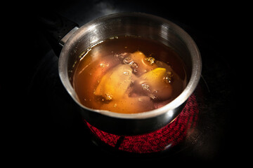 Melting beeswax in a metal pot on a ceramic stove for making natural material candles at home.