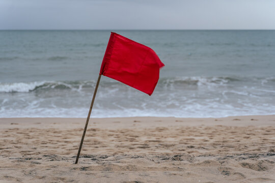 A red flag flying on a beach in Vietnam, signaling caution or warning.