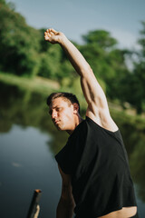 A man in athletic attire performs a stretching exercise in a vibrant outdoor park with water reflections.
