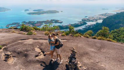 Couple kissing on a rocky overlook with tropical islands and turquoise sea in the background
