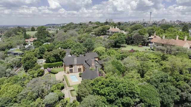 Drone flies over upper-middle class neighborhood on hill on sunny day in Johannesburg, South Africa