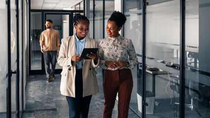 Two Businesswomen Collaborating in a Modern Office Corridor