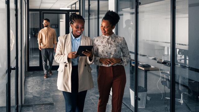 Two Businesswomen Collaborating in a Modern Office Corridor - Powered by Adobe