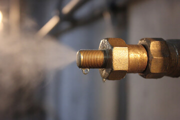 Steam escapes from a pipe connection showing water dripping in a workshop setting at a construction site