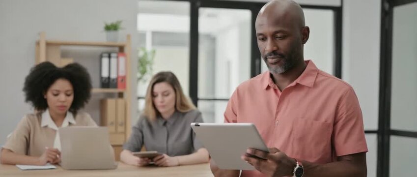 Focused Team in an Office Setting: A focused team of three individuals, immersed in their tasks, each utilizing technology and engaged in work within a modern office environment. 