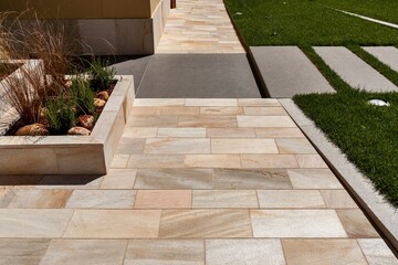 Contemporary outdoor design with beige limestone tiles, concrete inserts, and grass—clean lines and material contrast.