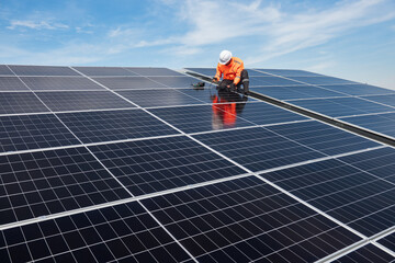 Technician installing solar panels on factory roof for green energy. A skilled technician in safety...
