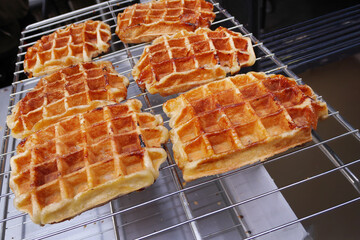 Freshly baked golden brown Traditional Liege waffles with caramelized sugar texture on a bakery cooling tray.