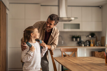 Obraz premium Father Preparing Young Daughter for School in Modern Kitchen Setting