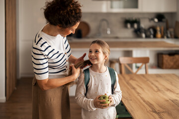 Mother Preparing Young Daughter for School in Cozy Modern Kitchen