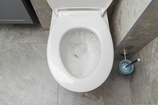 Water is running in the toilet in the bathroom, view from above.