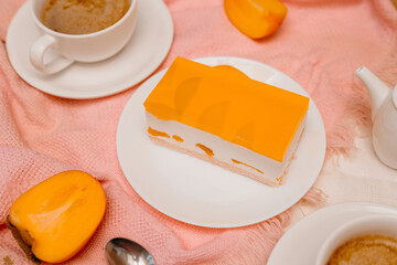 Peach cheesecake slice served with coffee cups on cozy table. Minimal dessert scene with warm light and soft colors.