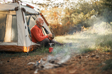 Senior Man Relaxing by a Campsite During a Scenic Sunset