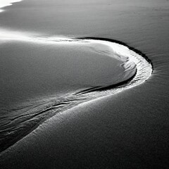 Curved waterline on black sand in monochrome style