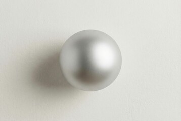 Matte silver ornament with soft shadow on textured plaster wall