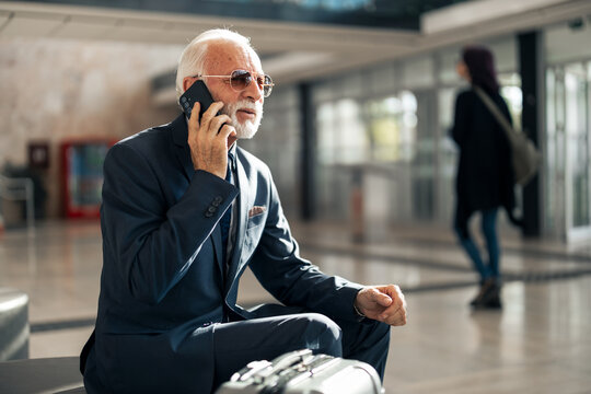 Senior Businessman Talking on Mobile Phone in a Modern Airport Lounge - Powered by Adobe