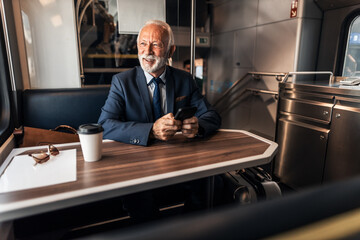 Senior Businessman Using Phone While Traveling on a Train