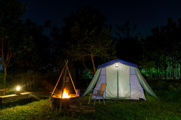 Nighttime camping tent in a forest clearing surrounded by nature