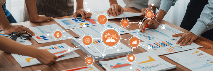 A dynamic scene showcasing a diverse team engaged in analyzing business growth data through various charts and documents on a collaborative workspace. Amity