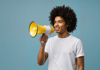 Young black man speaking through a megaphone against blue background  